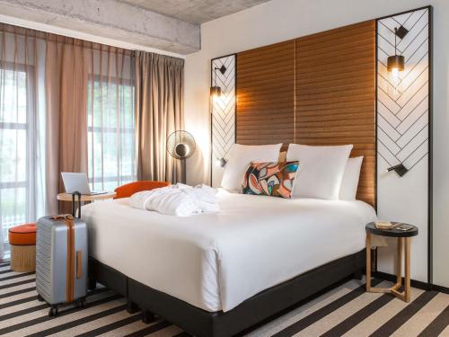 a hotel room with a large bed and a suitcase at Mercure Luxembourg Off Kirchberg in Luxembourg