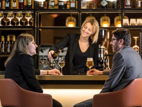 a woman pouring a glass of wine at a bar at Mercure Luxembourg Off Kirchberg in Luxembourg
