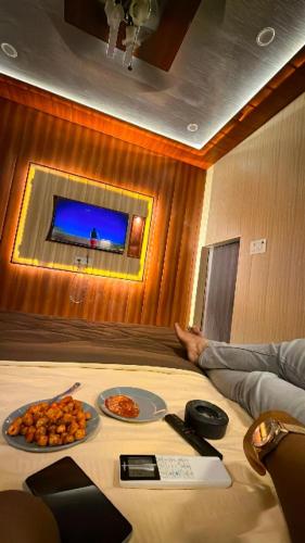 a person laying on a bed with a table with food at Sky Rooms & Cafe in Mughal Sarāi