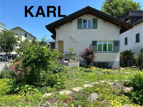 a white house with green windows and a yard at KARL Apartment in Interlaken