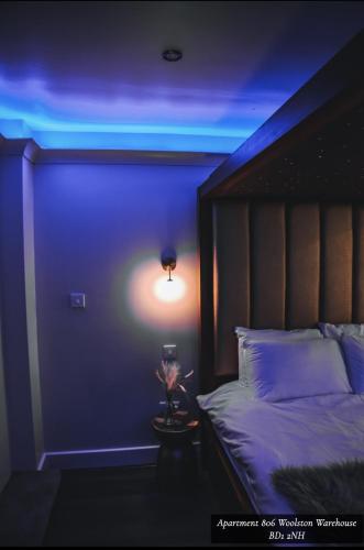 a room with a bed with a blue light at The Opulence Bradford in Bradford