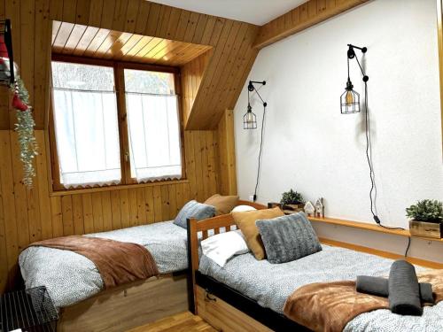 two beds in a room with wooden walls at Mira Moleta bienvenidos a Canfranc in Canfranc-Estación
