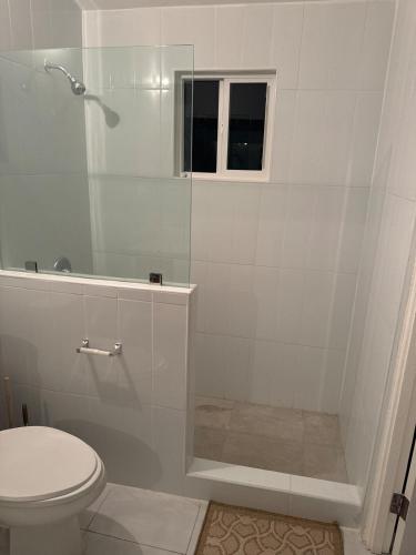 a white bathroom with a shower and a toilet at Gated Fortress In Old harbour in Old Harbour