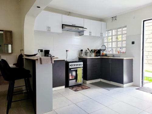- une cuisine avec des armoires en noir et blanc et un four dans l'établissement Nelle's Place, à Eldoret