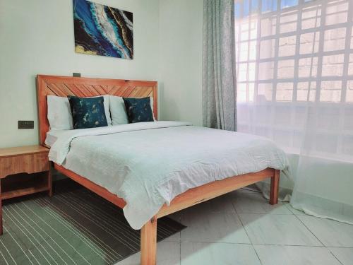 - une chambre avec un lit en bois et une fenêtre dans l'établissement Nelle's Place, à Eldoret