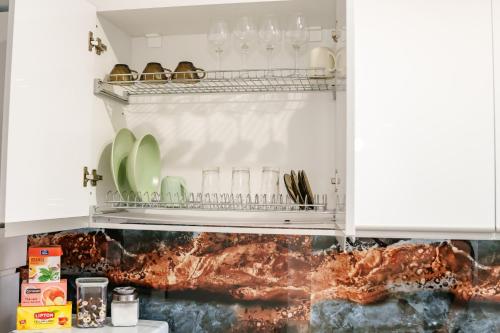 a kitchen with white cabinets with plates and glasses at AMBER Studio in Craiova