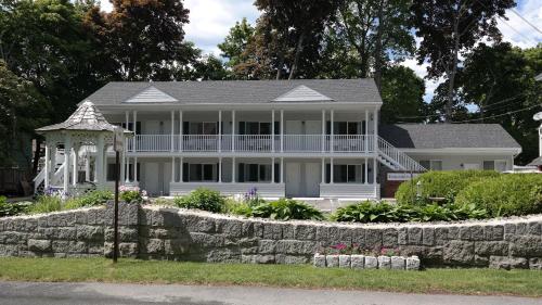 a large white house with a stone wall at Moseley Cottage Inn and The Town Motel in Bar Harbor