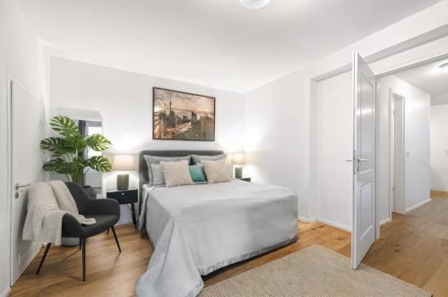 Un dormitorio blanco con una cama y una silla. en Lofty Torstr Apartments, 4 unique units from 1-3 bedrooms in Mitte, ideal for families & groups, from 2 up to 8 Guests, en Berlín
