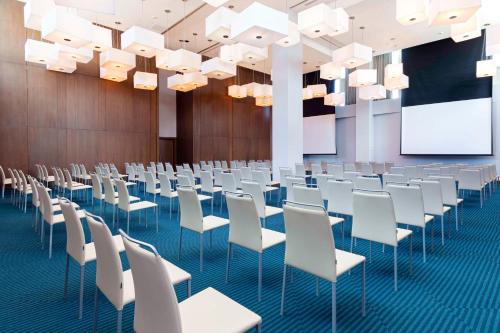 a conference room with white chairs and a projection screen at Avani Cancun Airport in Cancún