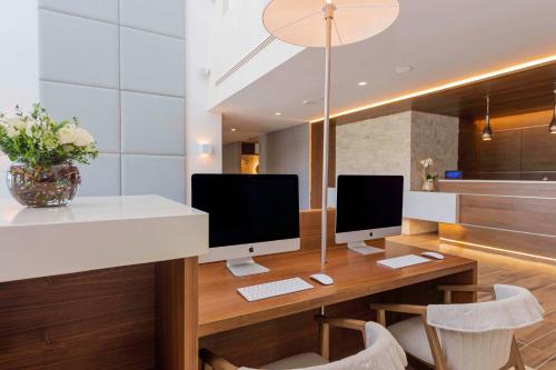 a desk with two computer monitors on top of it at Avani Cancun Airport in Cancún