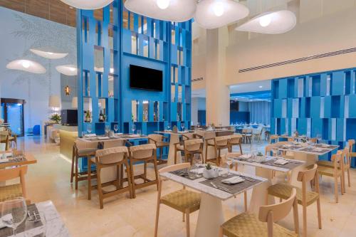 a restaurant with tables and chairs and a flat screen tv at Avani Cancun Airport in Cancún