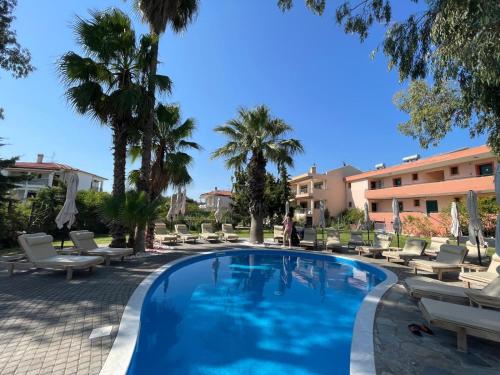 a swimming pool with lounge chairs and palm trees at Stefania Sun Apartments in Skála Nikíta