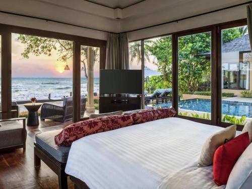 a bedroom with a large bed with a view of the ocean at Mövenpick Asara Resort & Spa Hua Hin in Hua Hin