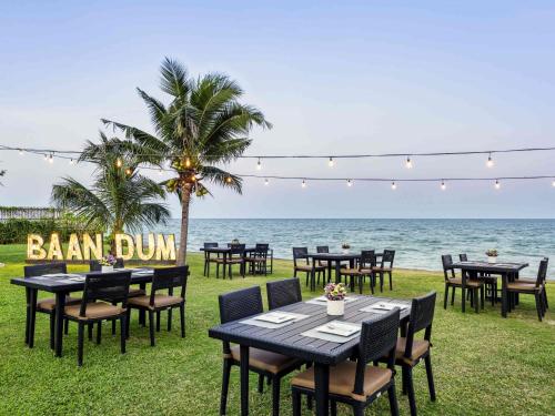 a group of tables and chairs in front of the ocean at Mövenpick Asara Resort & Spa Hua Hin in Hua Hin