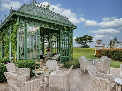 a green gazebo with white chairs and tables at Mövenpick Resort Khao Yai in Ban Wang Sai