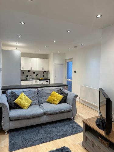 a living room with a gray couch and yellow pillows at Unique 3 Bed Flat and Cinema Room in Rogerstone