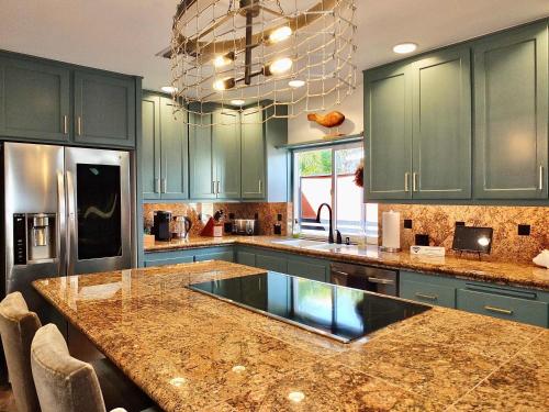 a kitchen with green cabinets and a granite counter top at Naples Luxury Retreat - 2 BDR Walk to Beach Dining & Shops in Naples