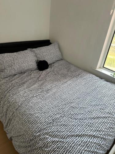 a bed with a black pillow and a window at Unique 3 Bed Flat and Cinema Room in Rogerstone