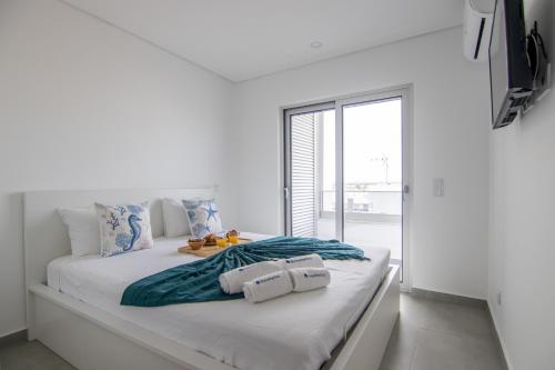 a white bedroom with a large bed with a window at Flat with Balcony near Casino by HostWise in Monte Gordo