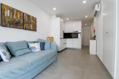 a living room with a blue couch and a kitchen at Flat with Balcony near Casino by HostWise in Monte Gordo