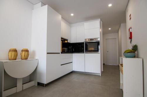 a kitchen with white cabinets and a refrigerator at Flat with Balcony near Casino by HostWise in Monte Gordo