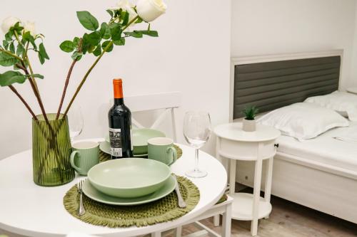 ein weißes Esszimmer mit einem Tisch und einer Flasche Wein in der Unterkunft AMBER Studio in Craiova
