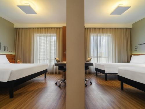 a hotel room with two beds and a desk at Ibis Styles SP Centro in Sao Paulo
