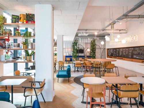 a dining room with tables and chairs and a chalkboard at ibis Styles Paris Romainville in Romainville