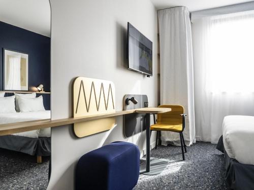 a hotel room with a desk and a bed at ibis Styles Paris Romainville in Romainville