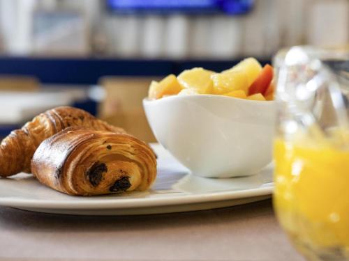 a plate of food with a pastry and a bowl of fruit at ibis Styles Paris Romainville in Romainville