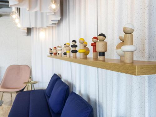 a shelf with wooden figurines on a wall at ibis Styles Paris Romainville in Romainville