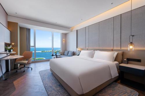 a bedroom with a large white bed and a desk at Crowne Plaza Weihai Binhai by IHG in Weihai