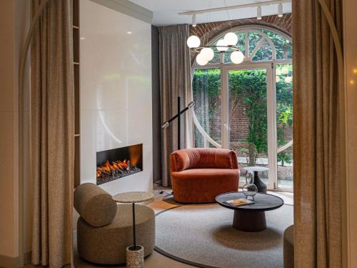 a living room with a chair and a fireplace at Mercure Liege City Centre in Liège
