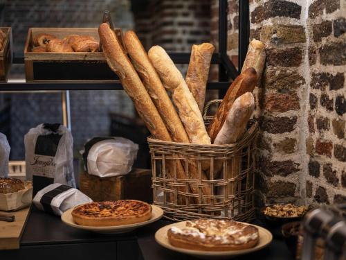 a basket of bread and pastries on plates on a shelf at Mercure Liege City Centre in Liège
