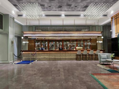 a lobby with a bar with people sitting at a counter at Mercure Shenzhen Sports Center Hotel in Shenzhen