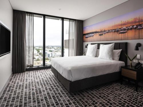 a bedroom with a large bed and a large window at Novotel Perth Murray Street in Perth
