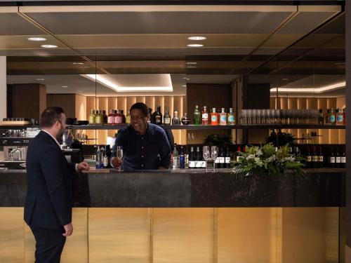 two men standing at a bar in a restaurant at Novotel Perth Murray Street in Perth