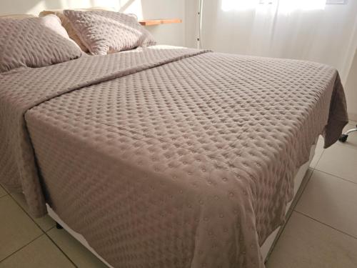 a bed with a pink comforter and pillows on it at Apartamento Charme e Aconchego da Serra in Petrópolis