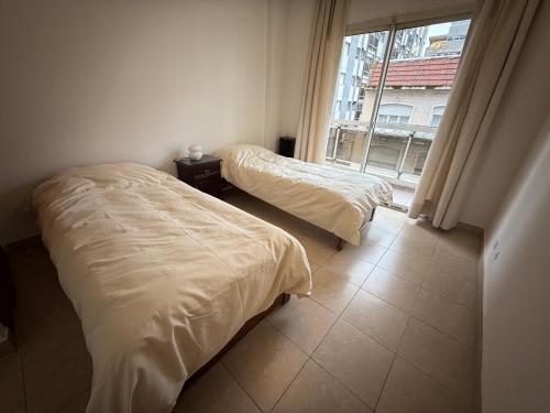 two beds in a room with a window at Edificio San Martin 2468 in Mar del Plata