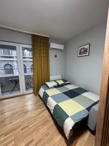 een slaapkamer met een bed en een groot raam bij Double Studio near University Square - 2 Balconies in Boekarest