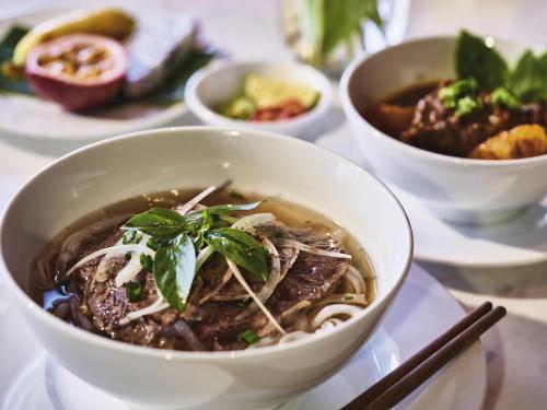 a bowl of soup on a table with other dishes at Mövenpick Villas & Residences Phu Quoc in Phu Quoc