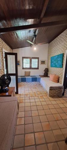 a living room with a bed and a brick wall at Fiquei In Pipa - Chalé 19 in Pipa
