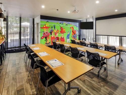 a classroom with tables and chairs and a large mural at Mercure Bendigo Schaller in Bendigo