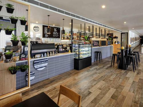 a restaurant with a counter and tables and chairs at Mercure Bendigo Schaller in Bendigo