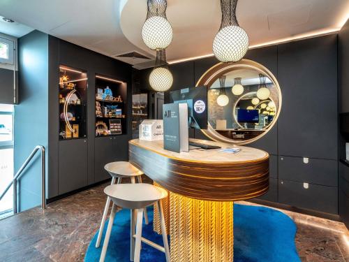 a bar in a store with two stools and a mirror at Mercure Hotel Luebeck City Center in Lübeck