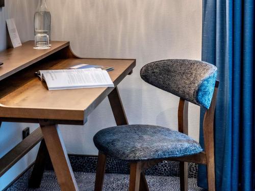 a desk with two chairs next to a table with a book at Mercure Hotel Luebeck City Center in Lübeck