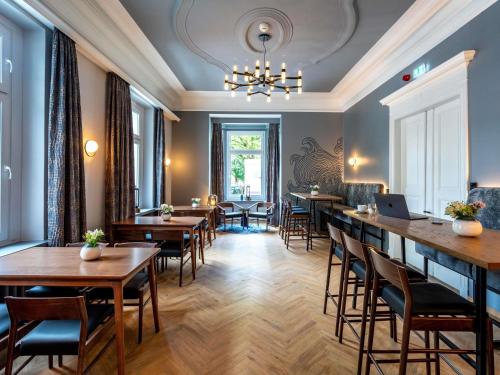 a restaurant with tables and chairs and a chandelier at Mercure Hotel Luebeck City Center in Lübeck