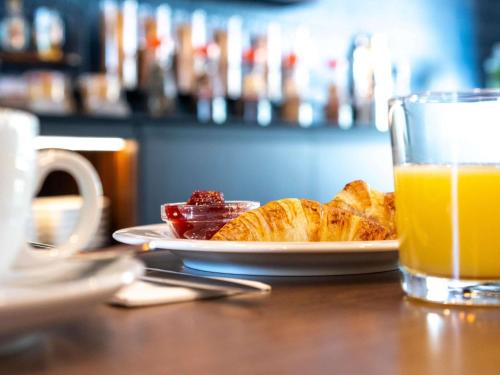 a table with a plate of food and a glass of orange juice at Mercure Hotel Luebeck City Center in Lübeck