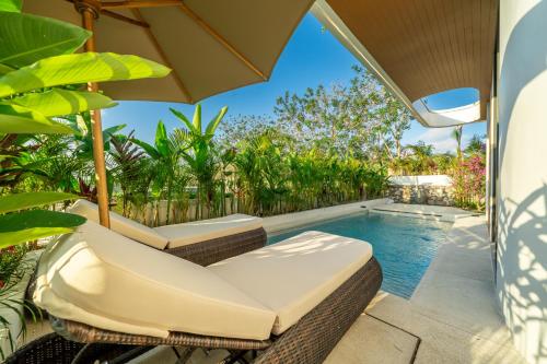 an outdoor patio with a pool and chairs and an umbrella at Ardhana 10 - Family-Friendly Villa - Private Pool - Prime Bali Location in Ungasan