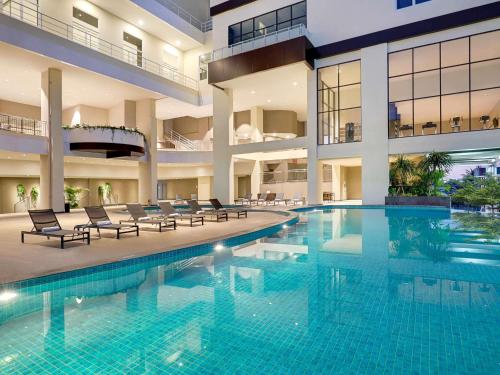 a large swimming pool in a building with chairs at Mercure Bengkulu in Bengkulu